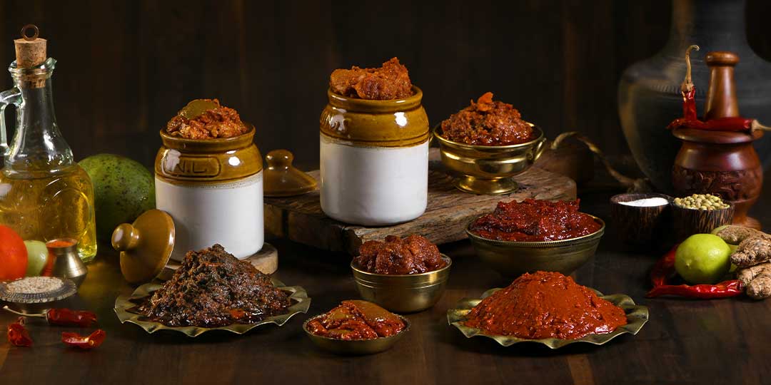 Handcrafted pickles in traditional ceramic jars and brass bowls, surrounded by whole spices